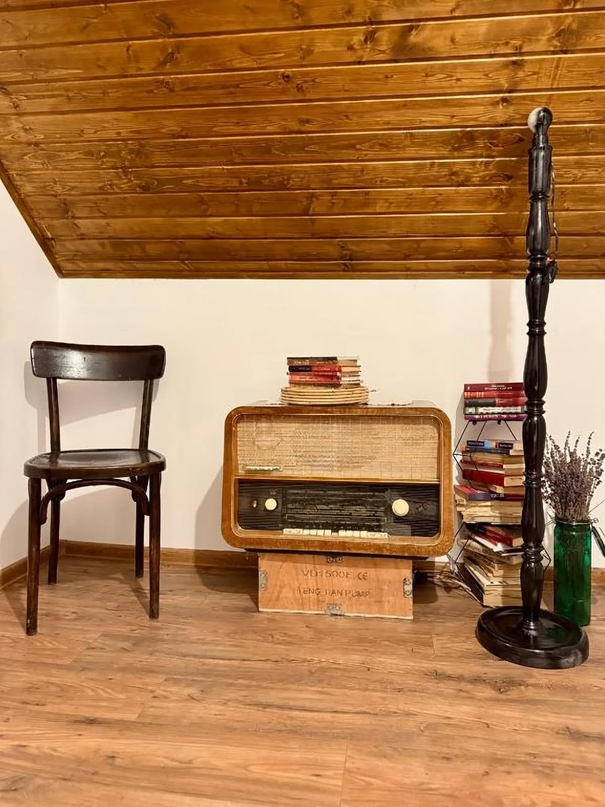 Radio vechi, scaun de lemn și cărți sub tavanul de lemn